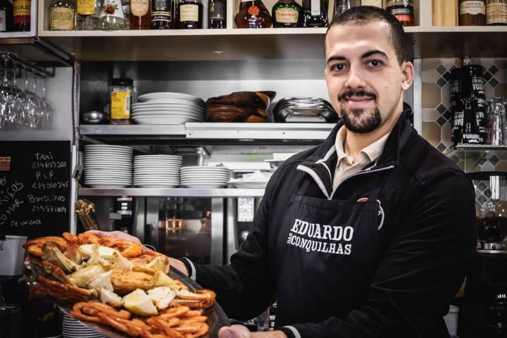 Un camarero enseñando una bandeja de mariscos