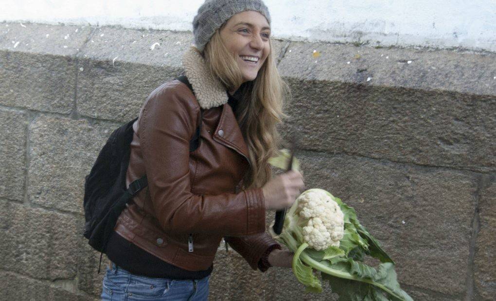 Lucía Freitas muy sonriente en el mercado con una coliflor en la mano.