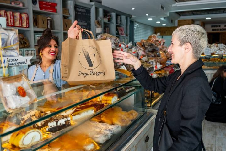 Silvia, la dependienta, dándole una bolsa a una clienta.