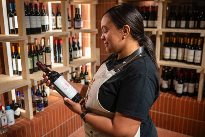 Carmela, una de las dependientas, mirando una botella de vino.