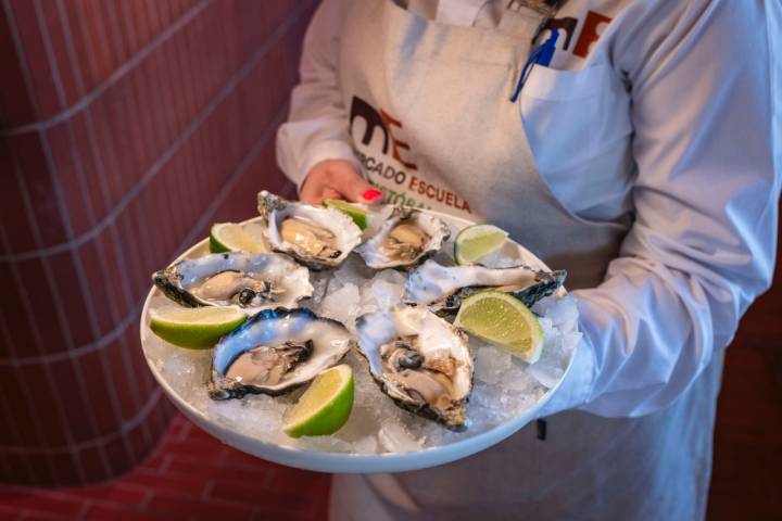 Una camarera con un plato de ostras.