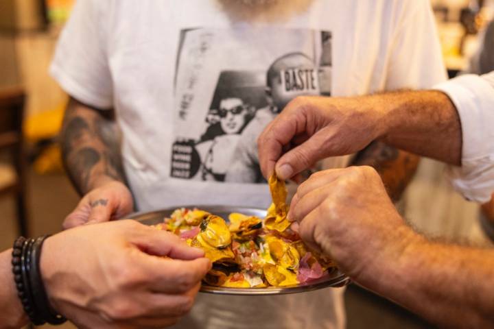 Varias personas cogiendo patatas fritas de un plato