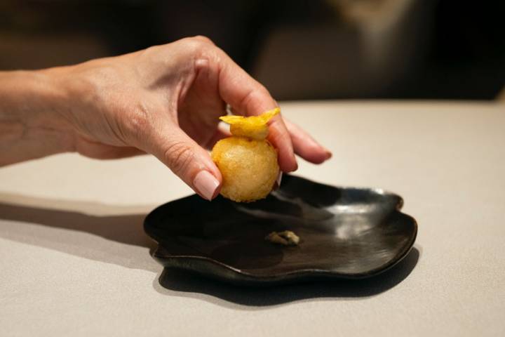 Un sabroso buñuelo de bacalao cremoso coronado con plátano maduro y un crujiente de yuca.