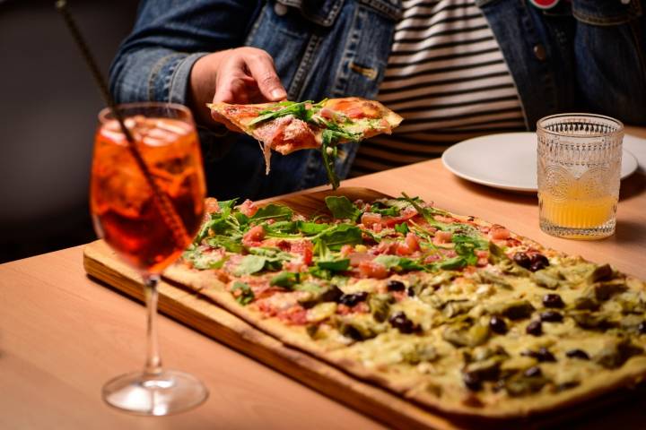 Aquí las pizzas son rectangulares, grandes, de masa fina, perfectas para compartir.