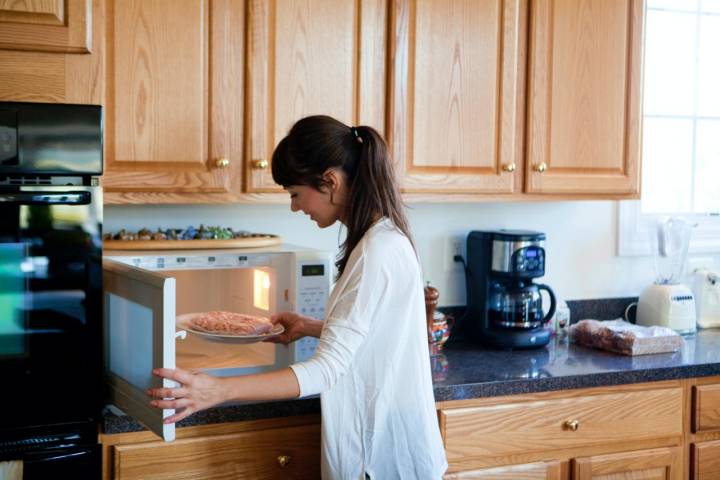 Mujer cocinando carne en el microondas