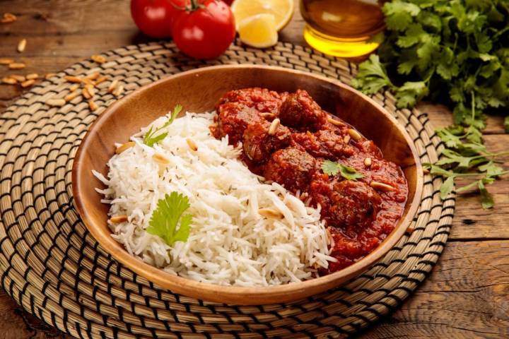 Plato de albóndigas en salsa de tomate con arroz de acompañamiento.