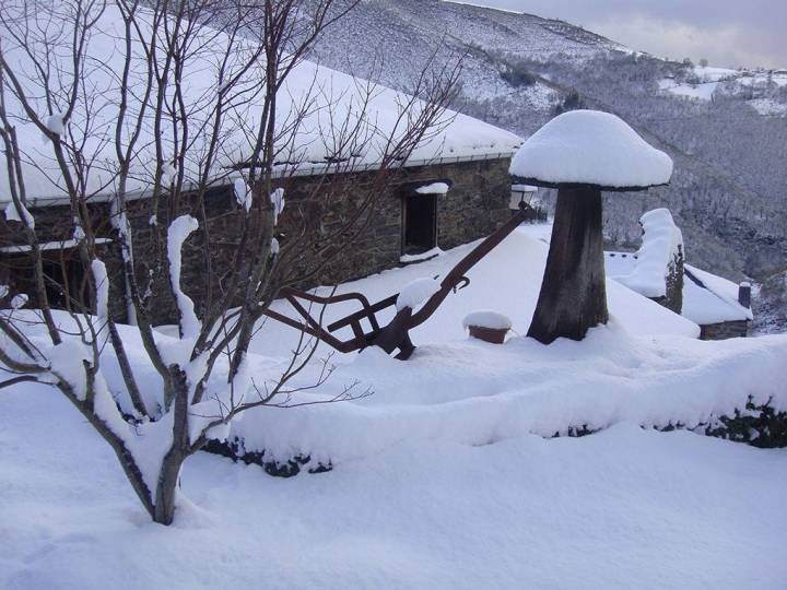 Imagen de una casa rural cubierta y rodeada por nieve
