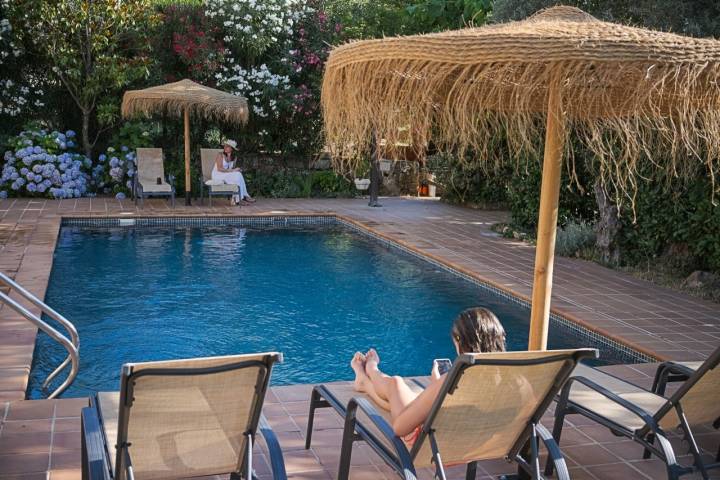 Dos personas toman el sol en la zona de hamacas de la piscina.