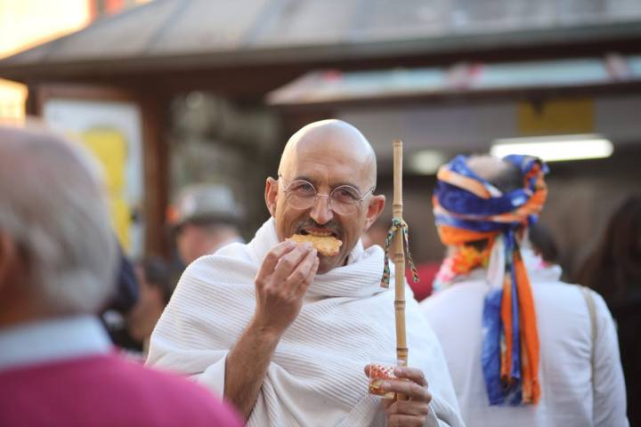 Un homabre disfraszado de Gandhi comiendose un tortillita de camarones en un lunes de corosen Cádiz