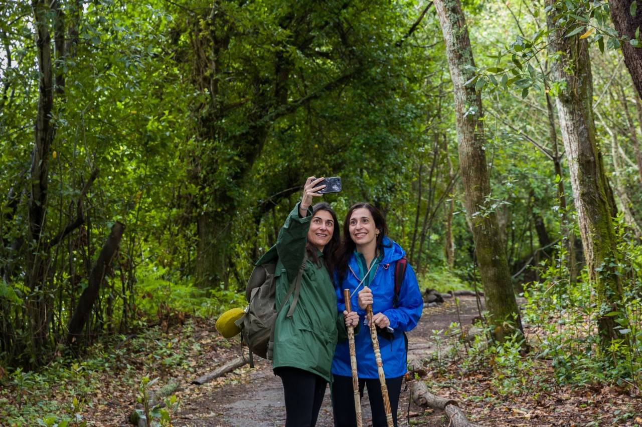Dos peregrinas haciéndose un selfie en un bosque.