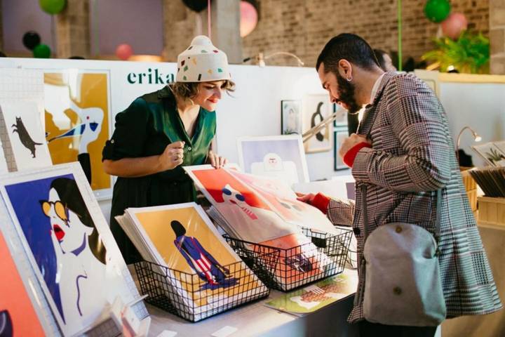 Un cliente observando unas láminas hechas por una artista.