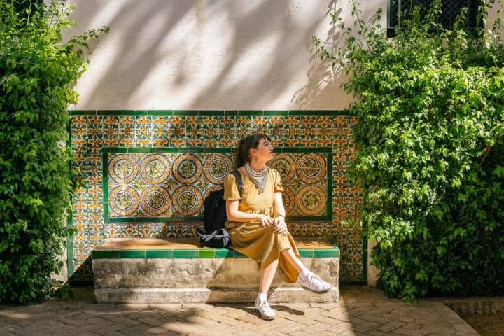 Woman resting on a bench made of ceramic tiles in a public park in Seville Spain surrounded with lush vegetation