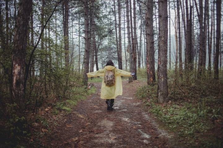 Una mujer con un chubasquero en un bosque.