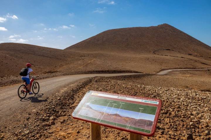 Los senderos se pueden recorrer a pie, en bici y, algunas zonas, en coche. Al fondo, el Volcán de La Caldera.