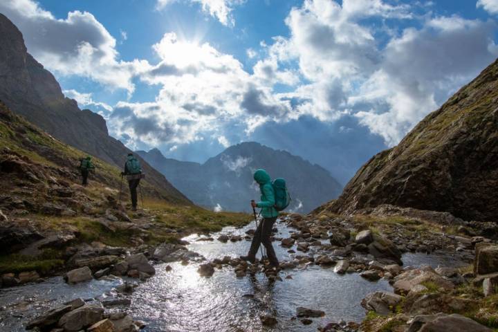 Senderistas cruzando un riachuelo camino al refugio de Ángel Orus en el Parque Natural Posets-Maladeta (Huesca).