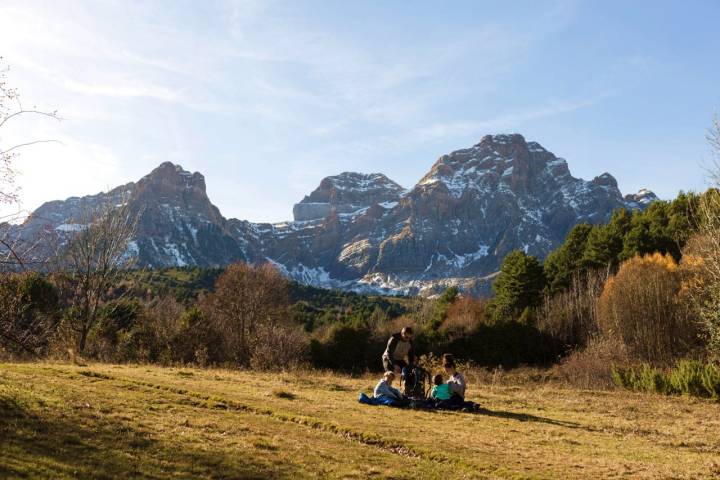 Una familia descansa en la pradera frente a la Peña Telera