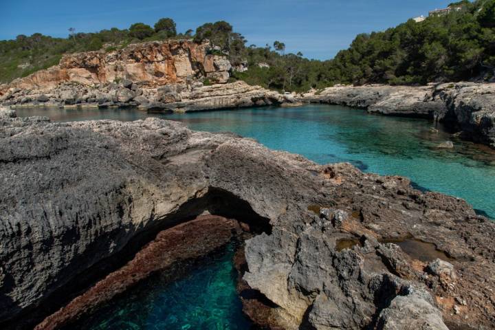 La cala está delimitada por rocas, lo que crea una sensación de estar nadando en una piscina natural.