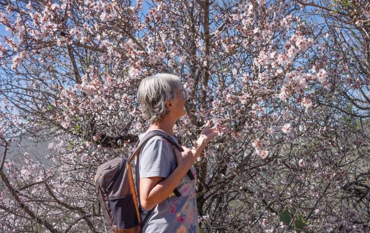 Mujer junto a un almendro en flor.