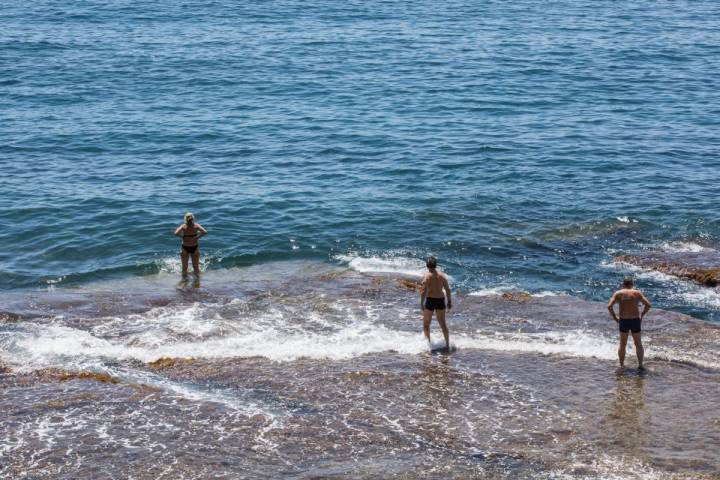 Gente bañándose en la orilla de la cala Mallorquín, en Calpe, Alicante.
