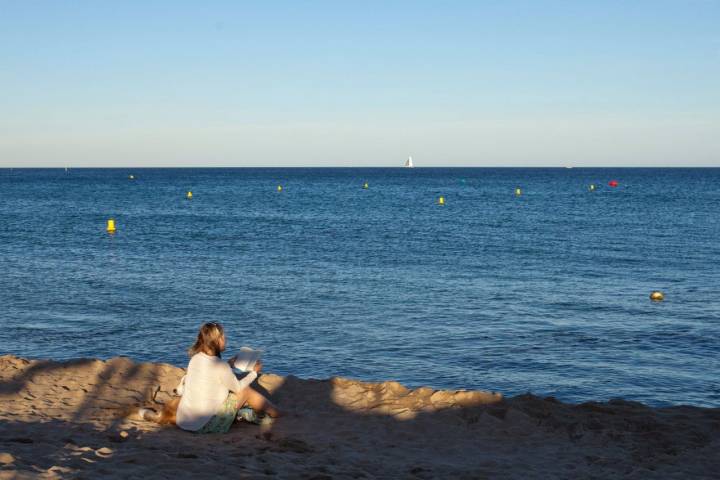 Una mujer leyendo en la playa de Bogatell (Barcelona).